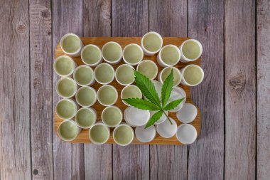 Yeşil taze ve kuru yapraklardan marihuana merhemi eski ahşap masada çiçek açar.