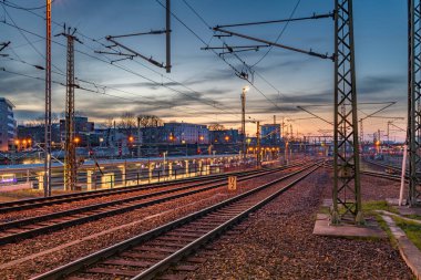 Dresden Almanya istasyonunda demiryolları ve elektrik direkleriyle güneşli bir gün batımı gecesi.
