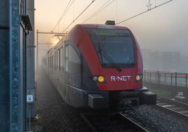 Yolcu trenleri Dordrecht Stadspolders Hollanda 'da sabah sisli tren durağında duruyor.