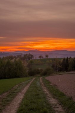Akşam Roprachtice köyünün yakınlarında, bulutlu güneşli bir akşamda, gün batımında.