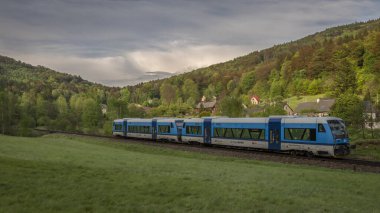 Mavi motorlu yolcu birimi Raspenava CZ 05 04 2024 yakınlarında güneşli bir günde mavi gökyüzünde tren kullanıyor.
