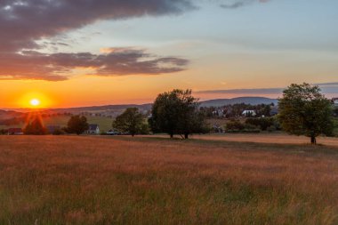 Krusne dağlarında gün batımı olan çayırlar Nova ves Horach köyünde renkli bir akşamda
