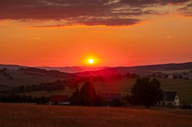 Krusne dağlarında gün batımı olan çayırlar Nova ves Horach köyünde renkli bir akşamda