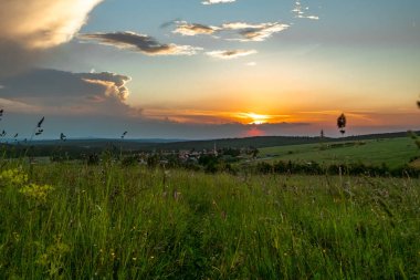 Yaz akşamında, bulutlu gökyüzü ile Bozi Dar kasabasının yakınında gün batımı