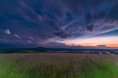 Yaz akşamında Bozi Dar kasabasının yakınında fırtınadan önce bulutlu gökyüzü ile gün batımı