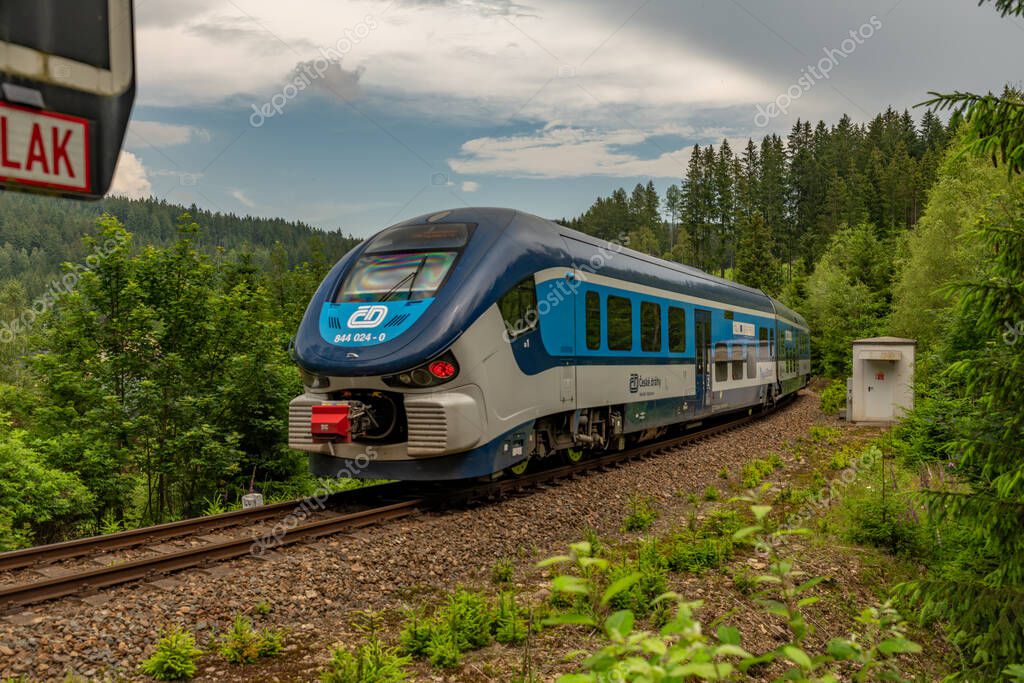 Train near small crossing of road in summer cloudy day in Potucky CZ 06 27 2024