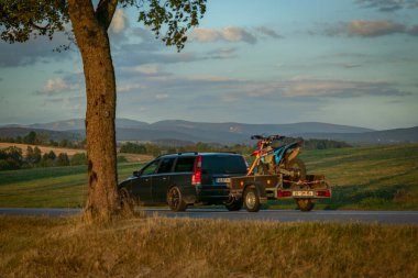Roprachtice CZ 09 07 2024 yakınlarında yaprak ağaçları ve kuru yaz çayırlarıyla dolu bir sokak.