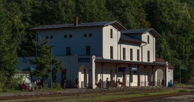 Jedlova CZ 09-2024 istasyonundaki yeşil sonbahar ormanları arasındaki beyaz istasyon binası.