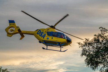 Acil sarı czech helikopteri gün batımında Ceske Budejovice CZ 10 09 2024 'te mavi gökyüzünde uçmaya başlıyor.