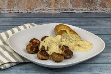 Köfteli tavuk köftesi, ekmek ve peynir sosu eski ahşap masada.