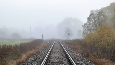 Sonbahar sisli ve soğuk sabahında tren rayları.