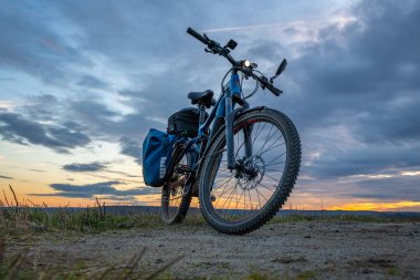 Dynin CZ 12 02 2024 yakınlarında, bulutlu renkte, sonbahar günbatımı olan elektrikli mavi bisiklet.