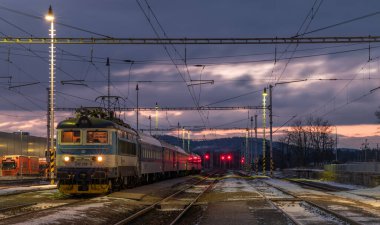 Nepomuk CZ 01 04 2025 'te soğuk kış bulutlu sabahında elektrik direkleri olan tren istasyonu.