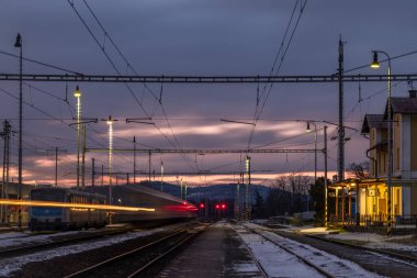Nepomuk CZ 01 04 2025 'te soğuk kış bulutlu sabahında elektrik direkleri olan tren istasyonu.