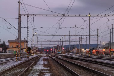 Nepomuk CZ 01 04 2025 'te soğuk kış bulutlu sabahında elektrik direkleri olan tren istasyonu.