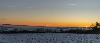 Winter frosty color view for sunset over road to Semily with silhouette of trees clipart