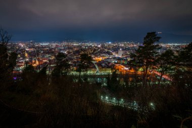 Kışın eski kuleyle tepeden bulutlu bir gece Graz Avusturya 'da soğuk bir akşam.