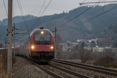 Demiryolu yakınında karanlık bulutlu bir sabah ve Kindberg Avusturya yakınlarındaki elektik birimi treni 02 01 2025