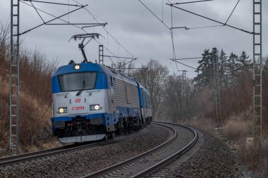 Kışın kara bulutlu bir sabah Tabor CZ 01 31 2025 yakınlarındaki tren rayları ve hızlı tren.