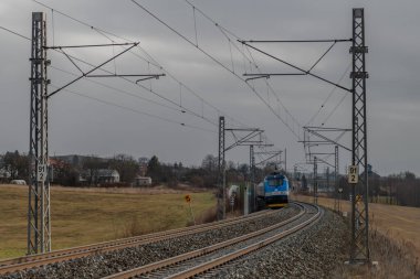 Chotoviny CZ 01 31 2025 yakınlarında kara bulutlu bir kış sabahı tren rayları ve hızlı tren.