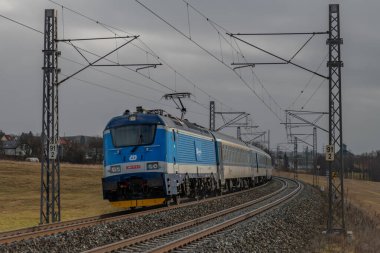 Chotoviny CZ 01 31 2025 yakınlarında kara bulutlu bir kış sabahı tren rayları ve hızlı tren.