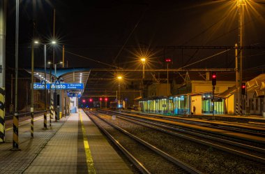 İstasyonda semafor ışıkları ve trenlerle bahar akşamı Mesto CZ 03 28 2025