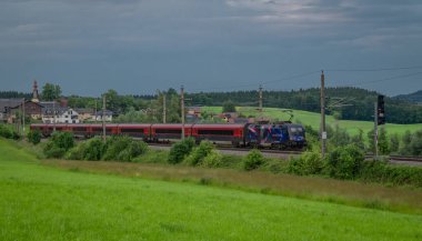 Weng Avusturya yakınlarındaki yaz bulutlu bir akşamda Avusturya trenleriyle elektrik hattı. 06: 25