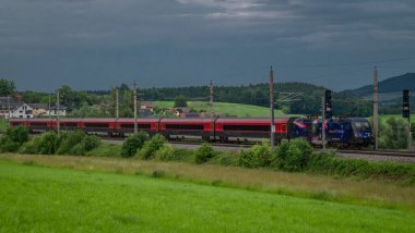 Weng Avusturya yakınlarındaki yaz bulutlu bir akşamda Avusturya trenleriyle elektrik hattı. 06: 25