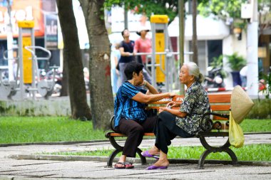 Ho Chi Minh City Vietnam 'da parkta oturan iki yaşlı kadın. Yaşlı kadın konuşuyor.