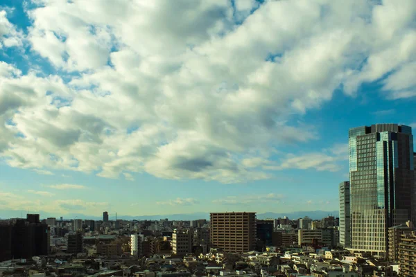 Image of sky, clouds, city and buildings, during the day