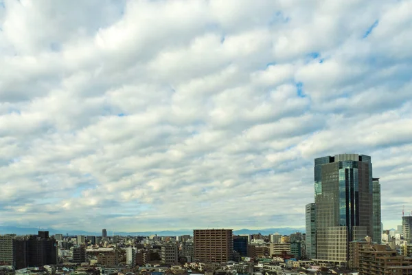 Image of sky, clouds, city and buildings, during the day