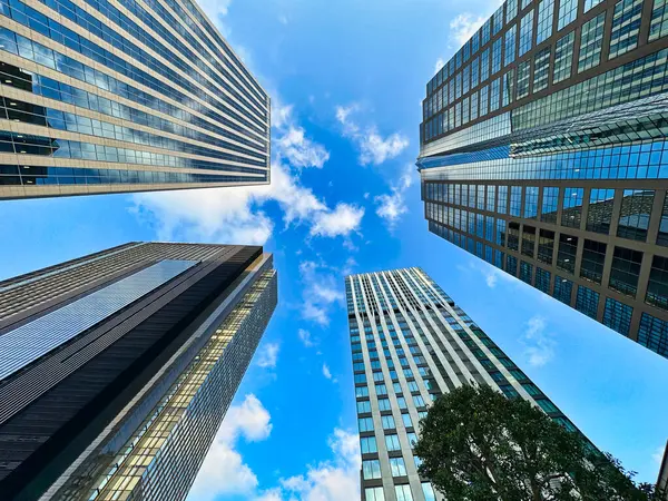 Şehirdeki yüksek binalar, mavi gökyüzü ve beyaz bulutlar, gündüz vakti