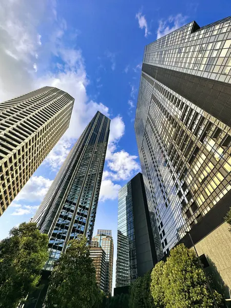 Şehirdeki yüksek binalar, mavi gökyüzü ve beyaz bulutlar, gündüz vakti