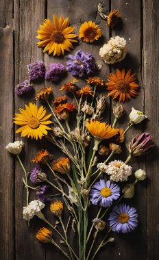 Kırsal ahşap bir masa üzerinde kurumuş ve taze çiçeklerin sanatsal düzlüğü..