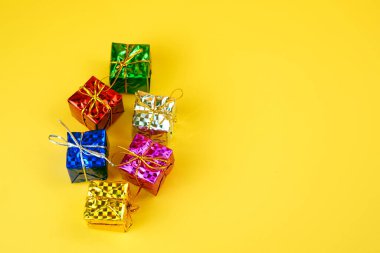 Stüdyoda sarı arka planda izole edilmiş altın telli metalik renkli hediyeler..