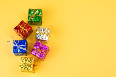 Stüdyoda sarı arka planda izole edilmiş altın telli metalik renkli hediyeler..