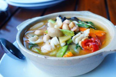 Baharatlı ve ekşi karışık sebzeler masada servis edilen beyaz seramik kasede..