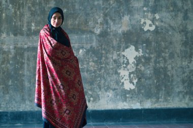 Siyah tesettürlü güzel kadın Jambi, Endonezya 'dan Batik' i kırsal duvara karşı giyiyor..