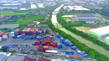 Flying over the river of Lamong East Java with the view of shipping containers by the river banks. Aerial shot.