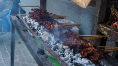 Goat satay on fire grill with bamboo fan in Salatiga, Central Java, Indonesia. Street Photography.