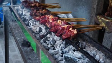 Goat satay on fire grill with bamboo fan in Salatiga, Central Java, Indonesia. Street Photography.