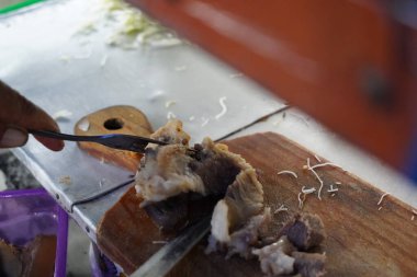 Biftek eti, tahta bir kesme tahtasının üzerinde parçalara ayrılıyor. Endonezya 'da erişte çorbası için hazırlık..