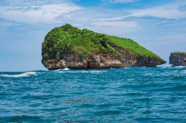 Okyanusta, Tanjung Kasap veya Kasap Burnu, Pacitan, Endonezya yakınlarında kaya oluşumu. Hareket halindeki bir tekneden alınmış. Seyahat Fotoğrafçılığı.