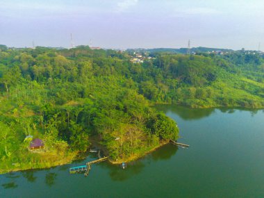 Lembah Jaibarang, Semarang, Endonezya 'da yemyeşil ağaçları, bitkileri ve evleri olan dalgalı bir gölün hava görüntüleri. Drone fotoğrafçılığı.