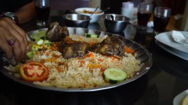 Yemek için Nasi Mandhi 'yi seçen yakın çekim elleri bu lezzetli yemeği seçme ve zevk alma samimi eylemini sergiliyor..