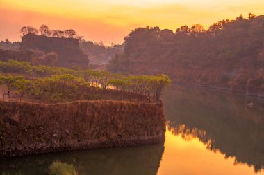 Ranu Manduro, Mojokerto, Endonezya 'da ağaçlarla birlikte gölün üzerinde gün doğumu. Doğa ve manzara fotoğrafçılığı.