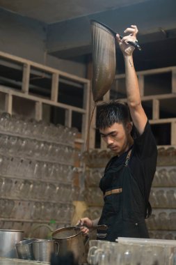 30 Temmuz 2023. Sabang, Aceh, Endonezya. Bir adam kahve dükkanında kahve hazırlarken bir çekim yapıyor ve kahveyi masanın üstünde sunuyor..