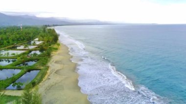 Blangpidie, Güneybatı Aceh, Endonezya 'daki güzel Bali Sahili' nde mavi okyanusla hava aracıyla mavi gökyüzü vuruşu. Gökyüzüne karşı kumlu sahilde yeşil çam ağaçları.