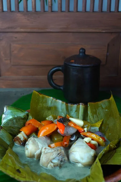 ガランアセムは 伝統的なジャワ料理は バナナの葉が並ぶ粘土板で提供され 鳥の目のチリ トマト ニンニク 酸っぱいヒト および他のさまざまなスパイスの混合物を伴います インドネシアの人気食品 — ストック写真
