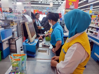 19 Ağustos 2023. Suraba, Doğu Java, Endonezya. Ödeme işlemi, QRIS teknolojili akıllı telefon kullanarak bir süpermarketin kasiyerinde Müslüman bir kadın tarafından gerçekleştirildi. İş ve finans editör fotoğrafı.